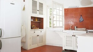 Eine Küche mit weißen Schränken, einem eingebauten Backofen und einem Fenster mit geöffneten Fensterläden.