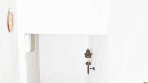 Eine Treppe mit hölzernem Geländer und roten Stufen, die zu einer Tür mit Schlüsselloch und einem kleinen dekorativen Gegenstand an der Wand führt.