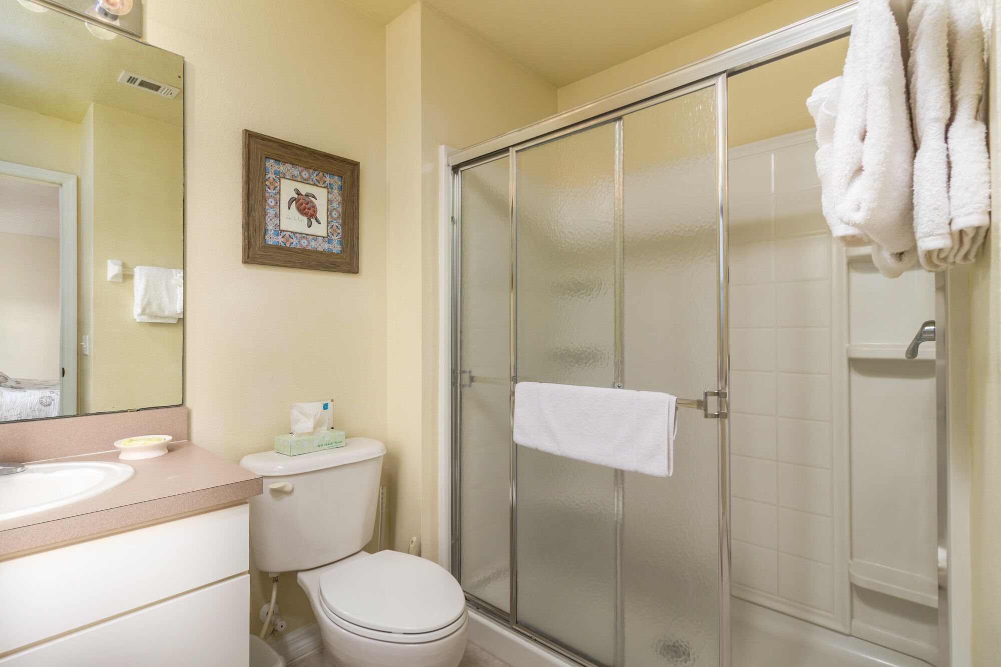 A bathroom with a toilet, sink, and a glass shower enclosure.