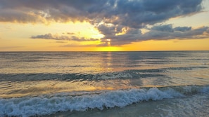 Un atardecer sobre un mar tranquilo con olas acariciando suavemente la orilla.