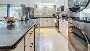 Una cocina moderna con una isla grande, electrodomésticos de acero inoxidable y vistas al exterior.