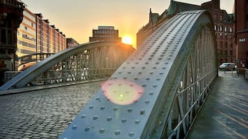 A pedestrian bridge with a curved metal structure and a cobblestone path beneath.