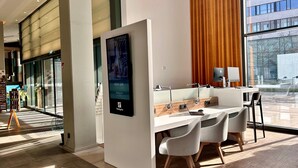 A modern hotel lobby with a reception desk, seating area, and large windows offering views of the outside. - Holiday Inn Hamburg - Hafencity by IHG (Hamburg)