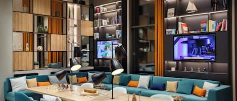 A modern living room with a large sofa, a dining table, and built-in bookshelves.