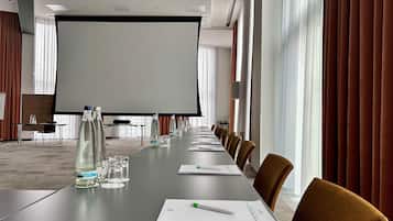 A conference room with a long table, chairs, a projector screen, and a whiteboard.