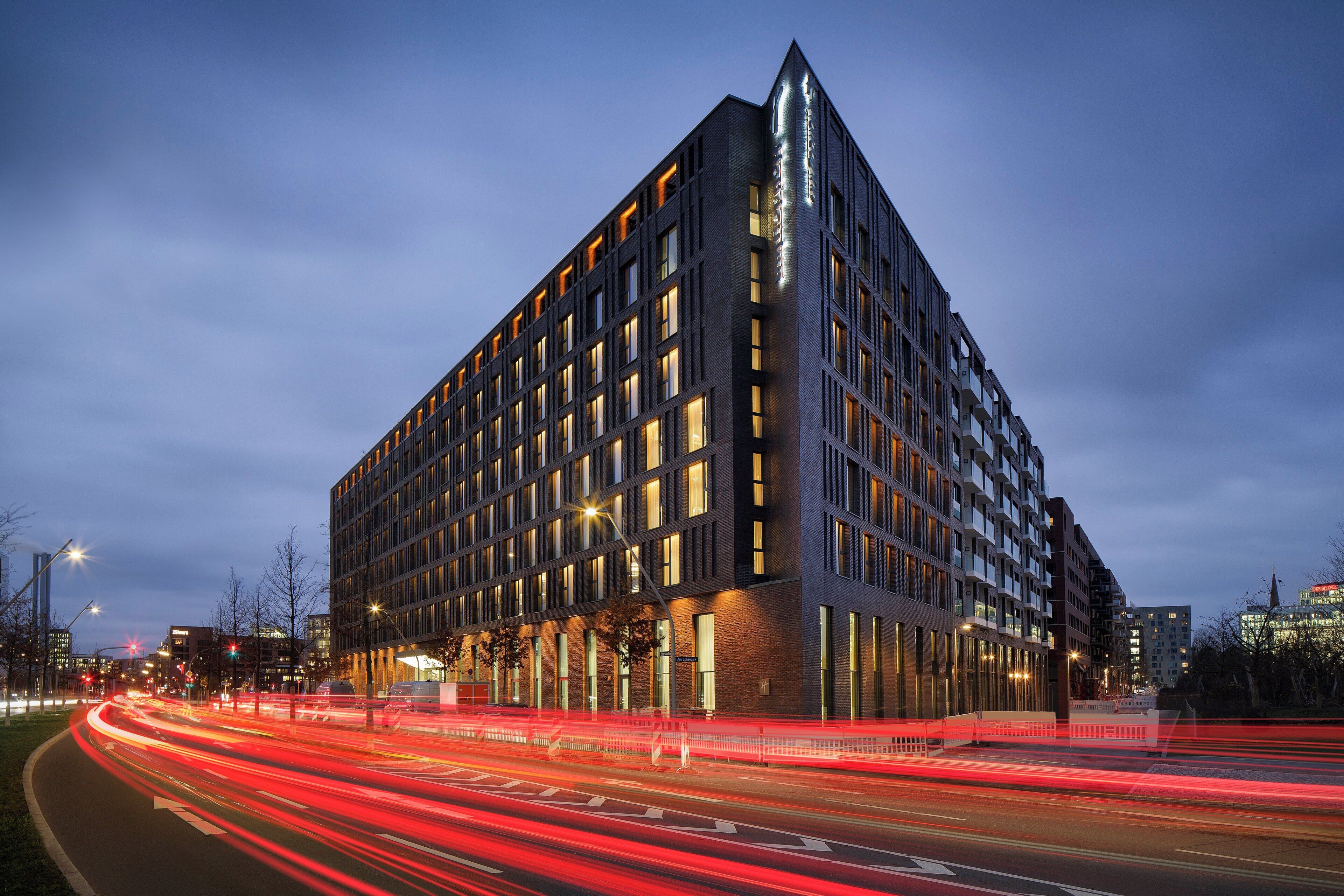 A modern building with a prominent corner design, multiple windows, and a well-lit facade.