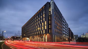 A modern building with a prominent corner design, multiple windows, and a well-lit facade.