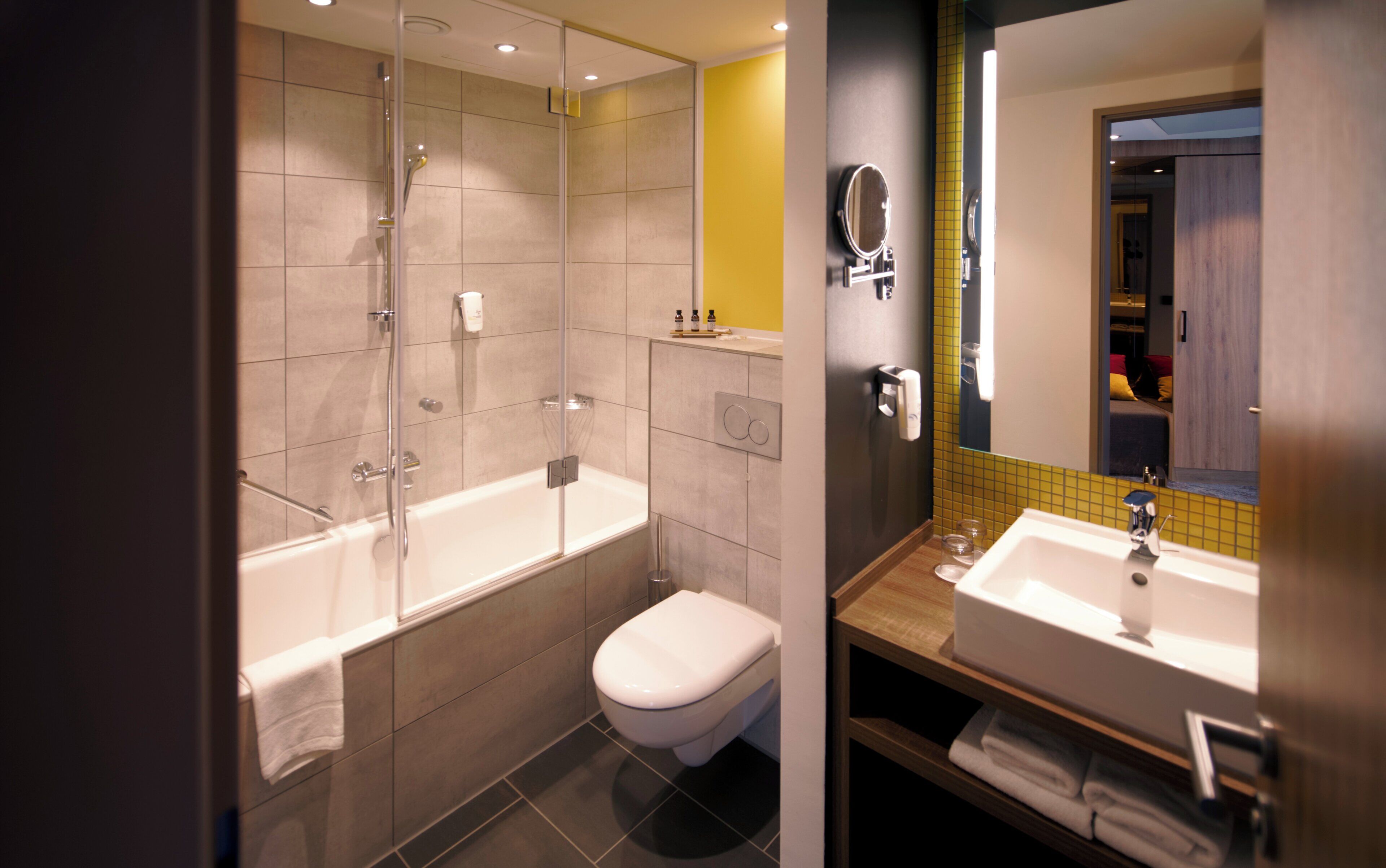 Een moderne badkamer met een douchecabine van glas, een toilet en een wastafel met spiegel.
