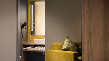 A modern bathroom with a yellow chair, a mirror, and a towel rack.