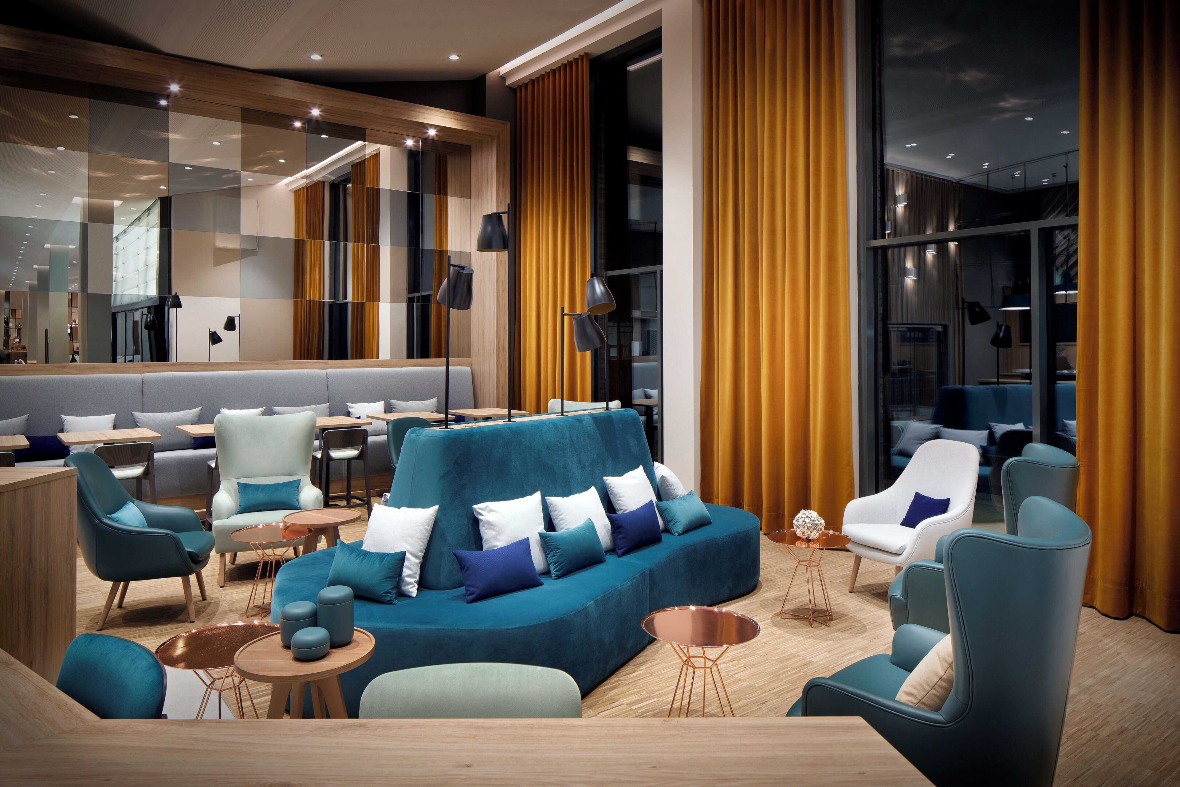 Un moderno espacio lounge con diferentes disposiciones de asientos, incluyendo sofás y sillones, y una zona de bar con mesas.