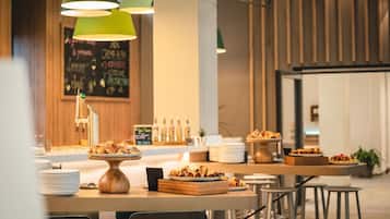 A modern restaurant interior with wooden tables, green pendant lights, and a chalkboard menu.
