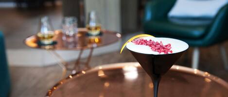 A martini glass with a garnish on a copper table in a modern interior setting.