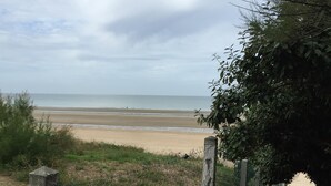 Une plage avec une vue sur la mer, une clôture et un sentier menant au rivage.