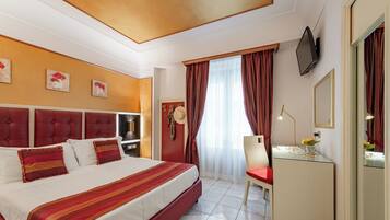Habitación de hotel con una cama grande, un escritorio con silla, televisión y ventana con cortinas.