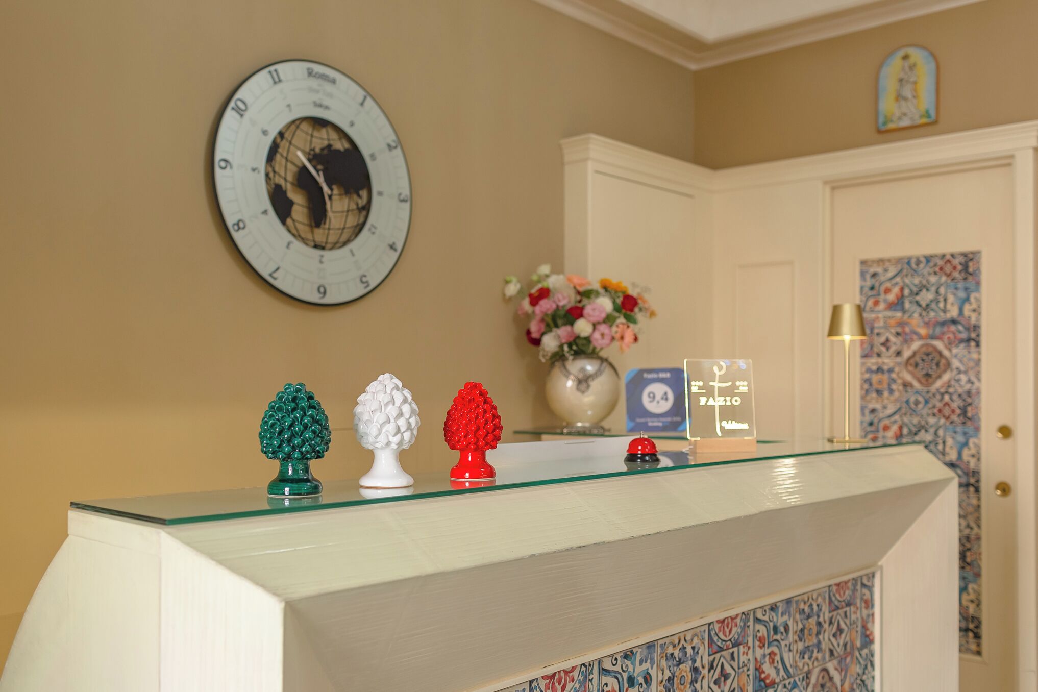 Una mesa de recepción con un reloj, un jarrón de flores y un cartel que indica las tarifas de las habitaciones.