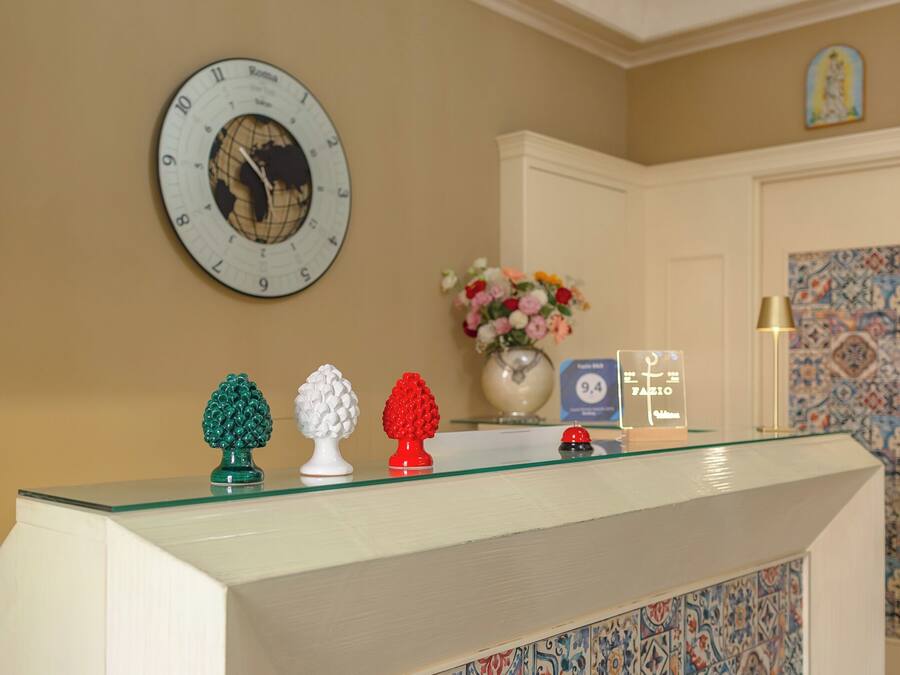 Una mesa de recepción con un reloj, un jarrón de flores y un cartel que indica las tarifas de las habitaciones.