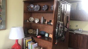 Une bibliothèque en bois ornée d’assiettes décoratives, de figurines et de livres.