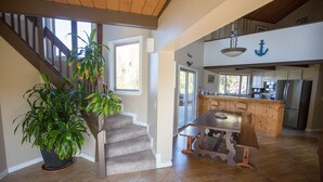 A spacious kitchen with modern appliances, a dining area with a wooden table, and a staircase leading to another level. - Pajaro Dunes House 81 (Watsonville)