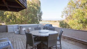 A covered outdoor patio with a round table and wicker chairs, a barbecue grill, and a hot tub. - Pajaro Dunes House 81 (Watsonville)