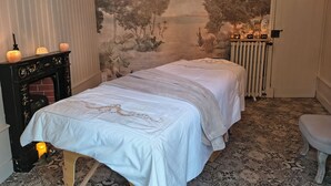 Une chambre avec deux lits, une cheminée, une fresque murale, un radiateur et une porte avec une serrure.