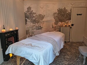 A room with two beds, a fireplace, a mural, a radiator, and a door with a lock.