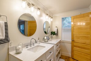 A bathroom with two sinks, a large mirror, and wooden doors. - Fairhope Downtown Cottage Sleeps 10  "Walk to Town" Lots of Parking and Garage (Fairhope)
