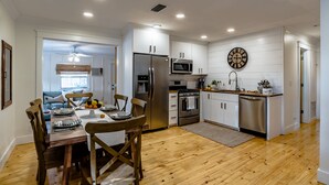 Una cocina moderna con armarios blancos, electrodomésticos de acero inoxidable y una mesa de comedor de madera con sillas.