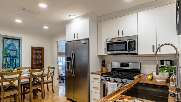 Una cocina moderna con electrodomésticos de acero inoxidable, sillas de madera y una mesa de comedor de madera.
