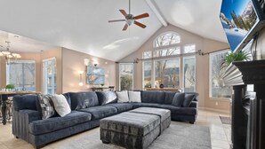 A spacious living room with a large sectional sofa, a ceiling fan, and a fireplace.