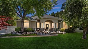 A two-story house with a stone facade, a front porch, and a well-maintained lawn.