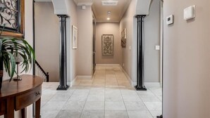 A hallway with two columns, a staircase, and a door at the end.