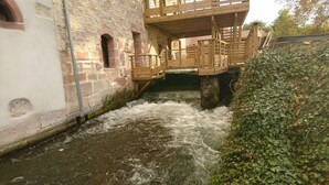 A stone building with a wooden bridge over a flowing river.