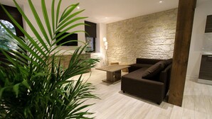 A modern living room with a stone wall, a wooden coffee table, a sofa, and a large plant.