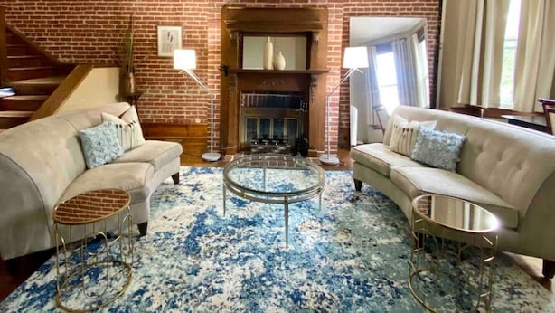 A living room with a brick fireplace, two sofas, a coffee table, and a staircase.