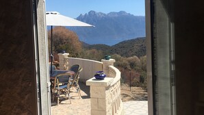 A patio with outdoor furniture, a stone wall, and a view of mountains. - Typical Corsican property, 3 bedrooms sleeps 6, view of the Gulf of Porto (Osani)