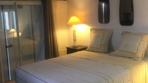 A bedroom with a bed, a nightstand with a lamp, a mirror, and a sliding door. - Typical Corsican property, 3 bedrooms sleeps 6, view of the Gulf of Porto (Osani)