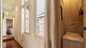Ein Korridor mit Holzboden, weißen Wänden und einem Fenster mit Vorhang.