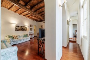 Un salon spacieux avec un plancher en bois, un canapé, un téléviseur et des tableaux encadrés accrochés au mur.