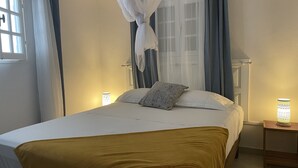 Makuuhuone, jossa on sänky, yöpöytälamppu ja ikkuna, jossa on verhot.