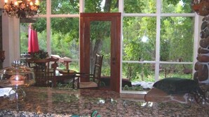 Una cocina con encimera de granito, una araña y ventanas amplias con vistas a un jardín.