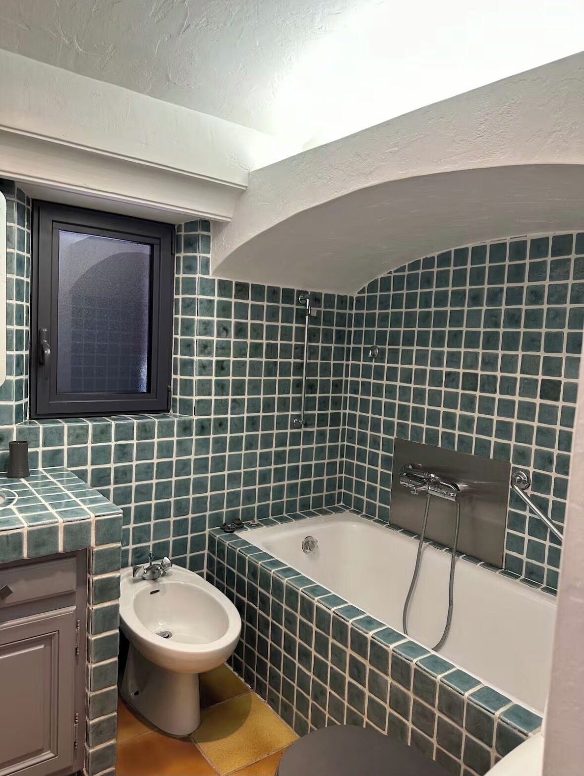 Une salle de bain avec une baignoire, un lavabo et une fenêtre.