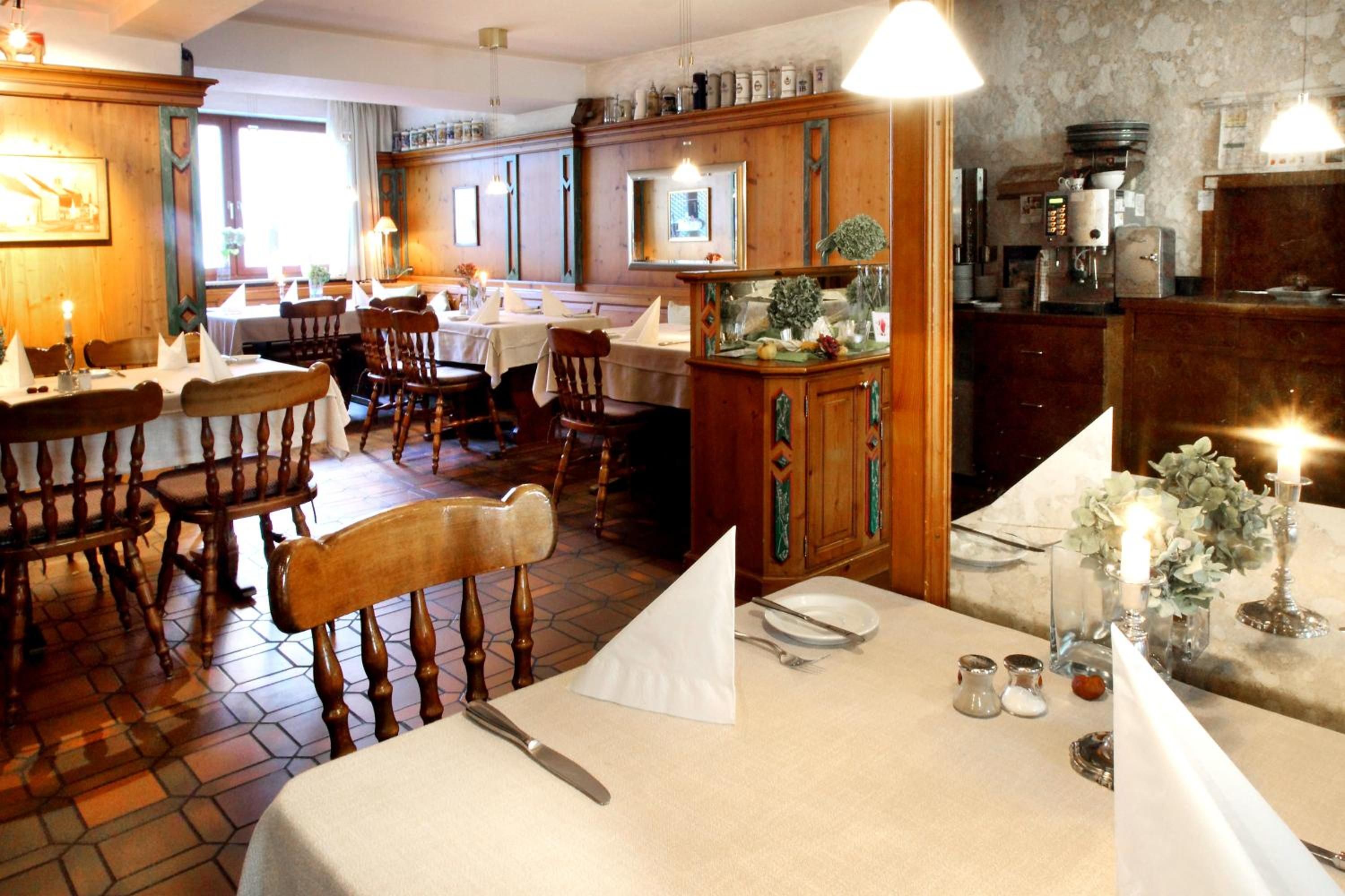 Un restaurante con mobiliario de madera, una zona de bar y un comedor con mesas dispuestas para el servicio.