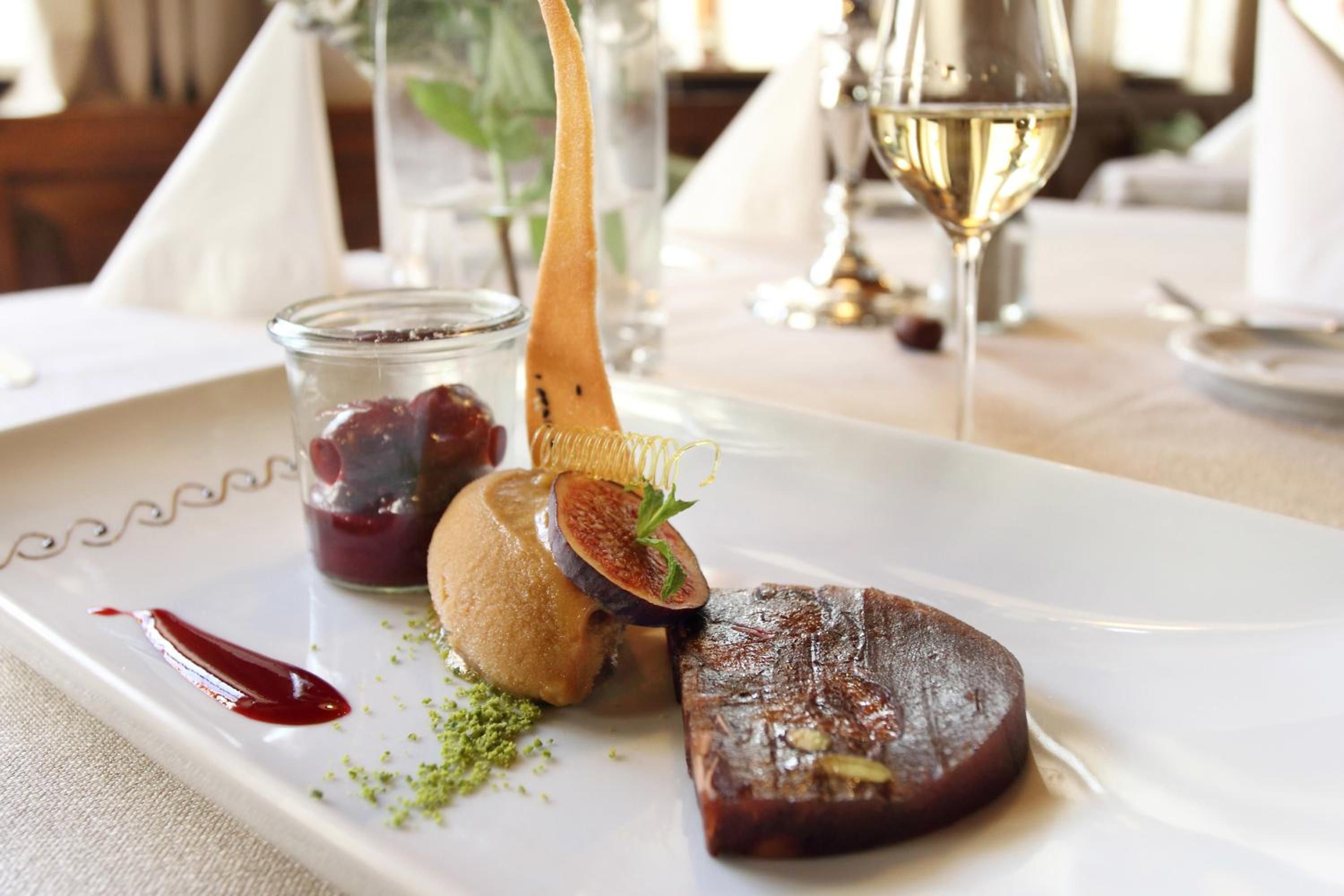 A plated dish with various food items, a glass of white wine, and a glass of red wine on a table.
