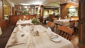 Een restaurant met gedekte tafels, houten stoelen en een klassiek interieur.