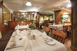 Un restaurante con mesas dispuestas para comer, con sillas de madera y una decoración clásica.