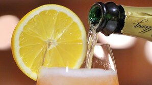 Een cocktail wordt in een glas geschonken, versierd met een citroenpartje.