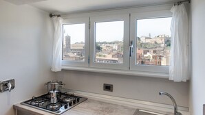 A kitchen with a gas stove, a pot, and a window with curtains.