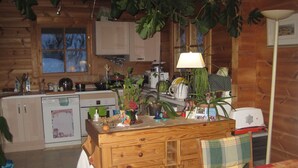 Une cuisine chaleureuse avec des meubles en bois, un îlot central agrémenté de divers objets, et un coin repas avec une table et des chaises.