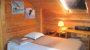 Une chambre confortable dans un chalet, avec un lit, un bureau et une lampe.