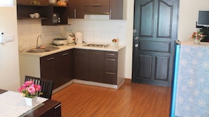 Uma cozinha compacta com armários marrom escuro, bancada branca e porta de armário de duas portas.